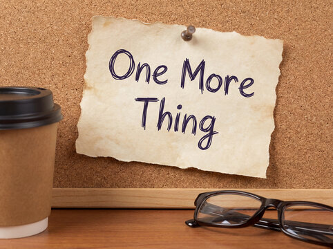 One more thing handwritten on a torn paper note pinned to a cork board, symbolizing an important reminder or final point