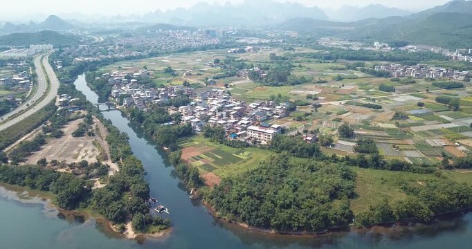 Aerial View of Rural Village Beside River and Farmland with Karst Mountains