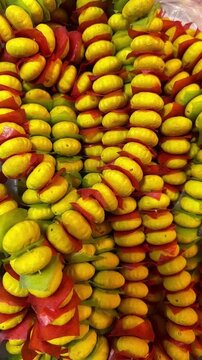 Top-down view of traditional Thai cookie garlands (Khanom Phing) made of colorful yellow, red, and green Thai tapioca starch cookies stacked together in strings.
