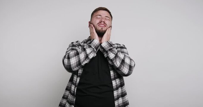 Man expresses different emotions while standing in front of a plain background, showcasing moments of frustration and thought in a simple setting