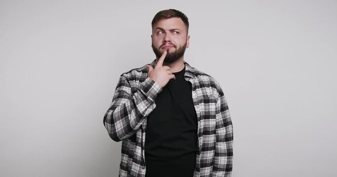 Man thinking while posing in a studio with gray background during day time