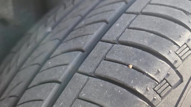 video footage showing detailed tire tread texture during inspection for possible puncture damage. Video clip focused on automotive maintenance and tire condition assessment.