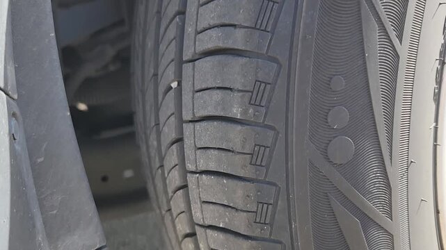 Video footage showing a close-up inspection of a vehicle tire tread. Detailed automotive maintenance footage highlighting tread pattern condition, tire wear evaluation, road safety assessment