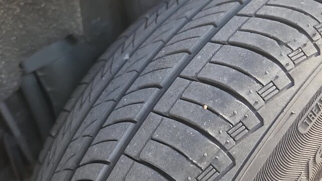 Video footage showing detailed inspection of a vehicle tire tread after locating puncture damage. Automotive service footage focused on tire condition assessment, maintenance procedures, and vehicle s