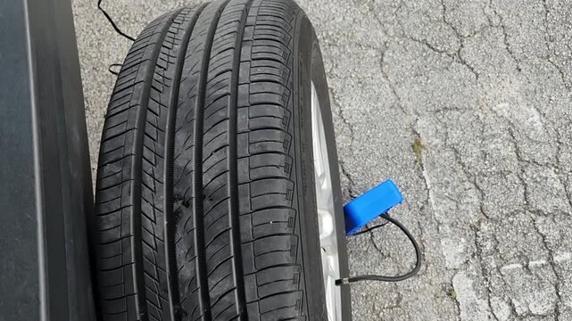 Deflated Vehicle Tire Being Inflated with Portable Tire Inflator After Repair