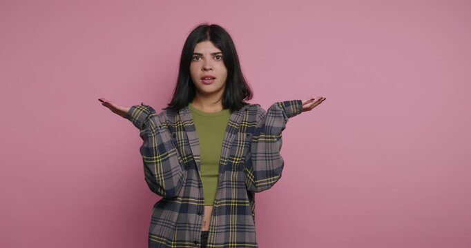 Young woman gestures and expresses thoughts in studio with pink background during creative session in day time