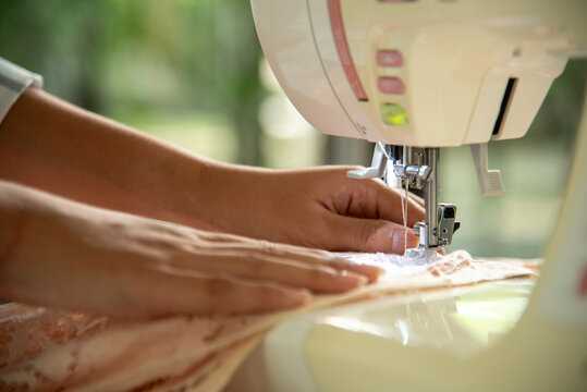 Close up woman hand use sewing machine. Entrepreneur fashion designer in textile business sew new retail clothing collection. Close up hands working in seamstress, designer working on fabric concept