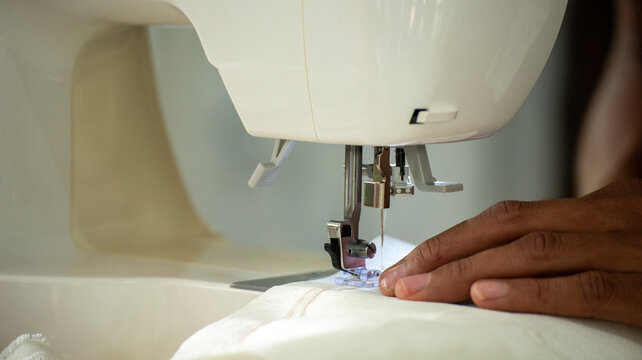 Close up woman hand use sewing machine. Entrepreneur fashion designer in textile business sew new retail clothing collection. Close up hands working in seamstress, designer working on fabric concept