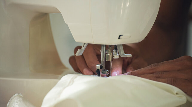 Close up woman hand use sewing machine. Entrepreneur fashion designer in textile business sew new retail clothing collection. Close up hands working in seamstress, designer working on fabric concept
