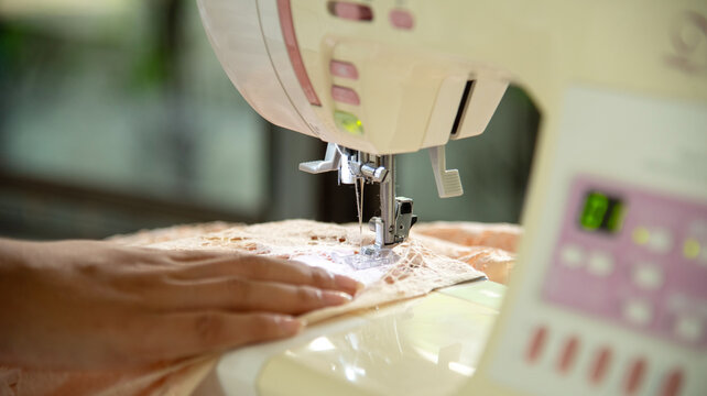Close up woman hand use sewing machine. Entrepreneur fashion designer in textile business sew new retail clothing collection. Close up hands working in seamstress, designer working on fabric concept
