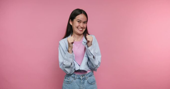 Smiling person in a pink background shows excitement and joy while posing for the camera in a playful manner