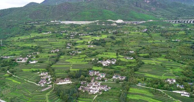 Aerial view of terraced farmland and rural village in a green mountain valley