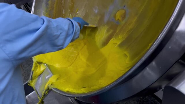 Prepared food filling being transferred from an industrial mixing kettle into containers for weighing and batch control. Food manufacturing process supporting product consistency, quality assurance, a