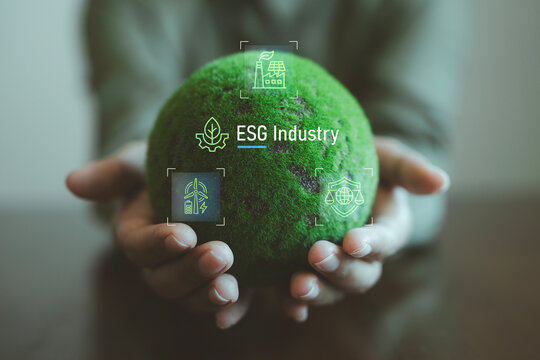 ESG industry eco technology concept business person holding green moss globe with holographic sustainable manufacturing renewable energy and environmental protection icons