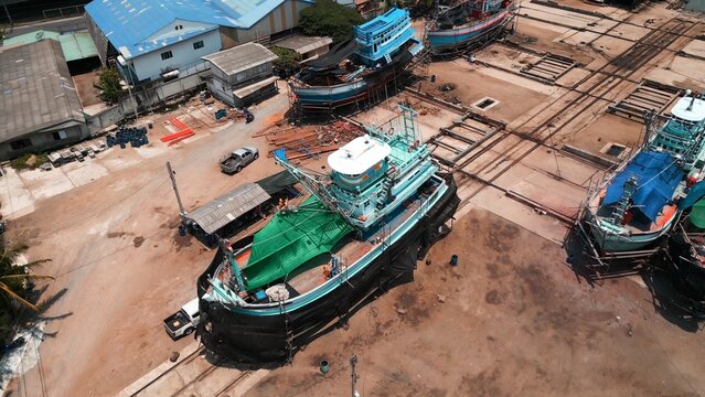 Fishing boats undergoing construction and repair in a busy industrial shipyard