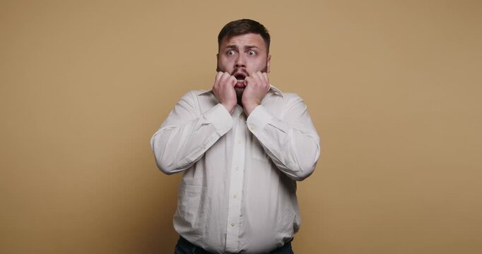 Man expresses surprise and joy in fun facial reactions in a studio setting with a plain background