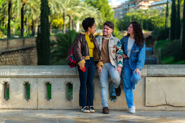 Fototapeta premium Group of diverse urban friends standing together, communicating, and smiling happily in an outdoor city park, enjoying a casual social gathering on a sunny daytime