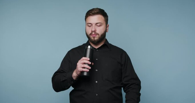 Man enjoys drink and shares thoughts with a smile and gestures in a simple studio setting