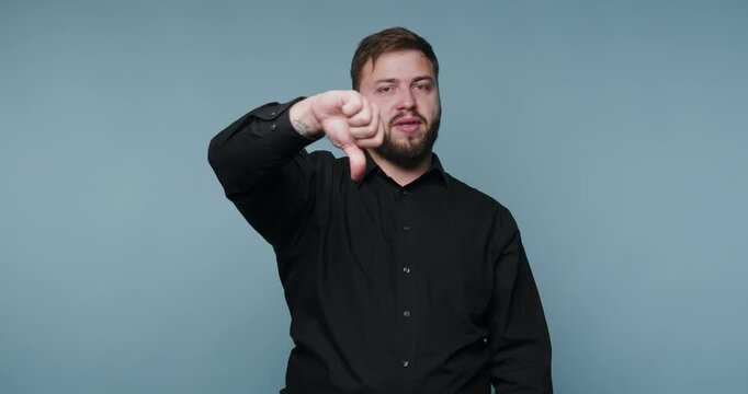 Man shows thumbs down gesture while standing against a blue background in a series of four frames during day time