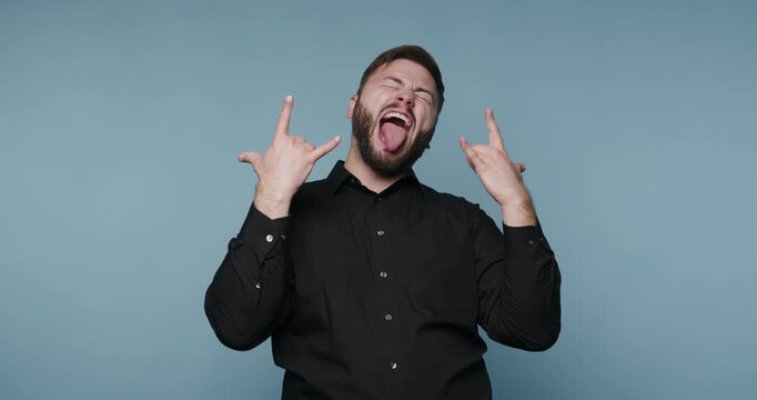 Man makes hand signs showing rock music culture in a studio background during a performance