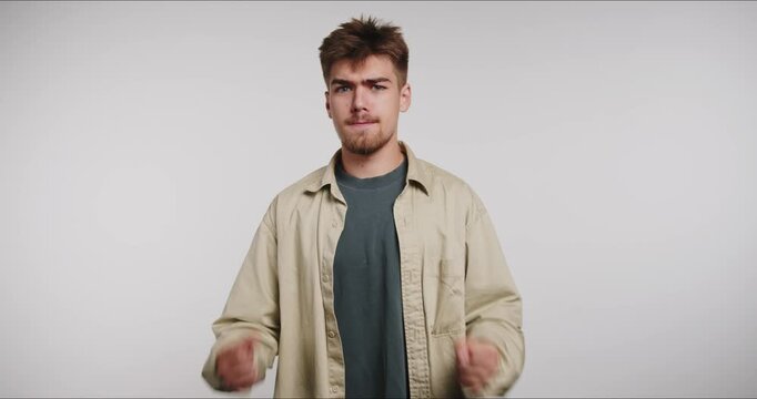 Man shows different facial expressions and hand gestures while standing in a plain room