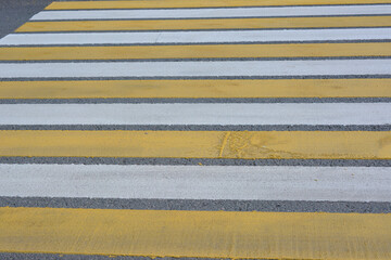 Fototapeta premium Yellow and White Striped Crosswalk on Asphalt Road close up