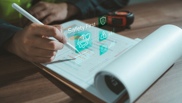 Zero accident and safety first concept industrial worker using stylus on document with holographic risk assessment dashboard and protection hard hat icon