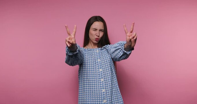 Smiling girl shows peace signs in front of pink background in different poses