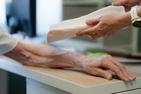 Treating arm fracture with bandage in clinic. Nurse and caregiver applying cast with attention, gentleness and professionalism. Fracture treatment process and bone healing in clinical setting