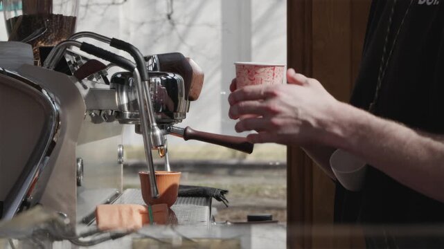 Pouring steamed milk into red paper coffee cup