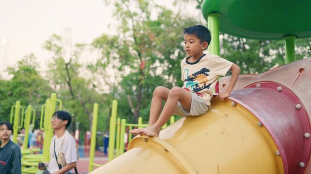 Little asian boy enjoy climbing on slider playground exercise public park
