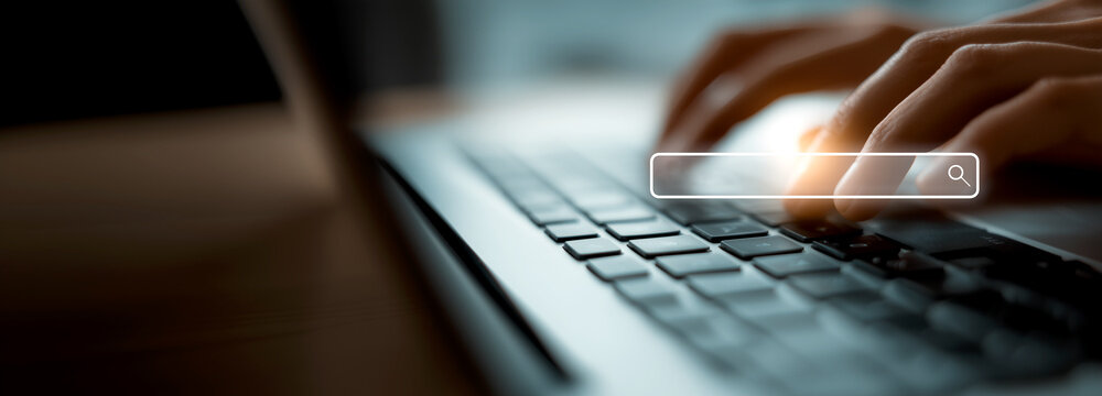 Close up of hands typing on laptop keyboard with digital search bar overlay, concept of internet browsing, SEO and online research