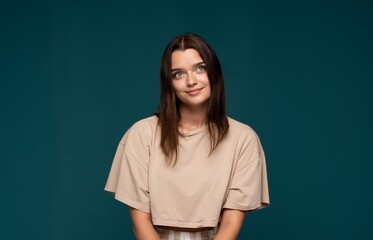 Obraz premium Young woman looking up with thoughtful expression, daydreaming with ideas and inspiration on blue background