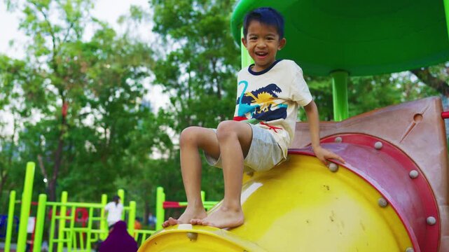 Little asian boy enjoy climbing on slider playground exercise public park