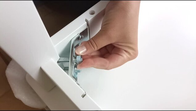 Assembly of a table frame by attaching a table leg with metal brackets, bolts and nuts. Furniture installation process focused on fastening structural components.