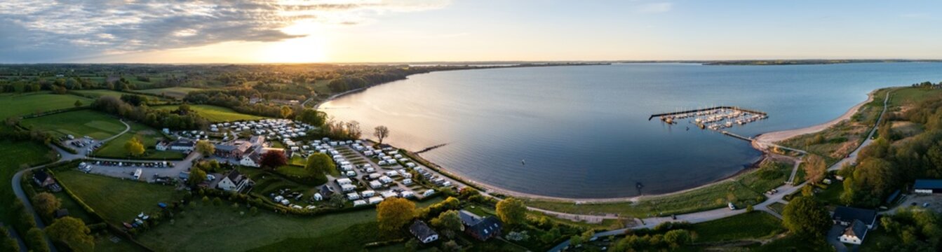 Aerial view of Bockholmwik featuring a campsite and marina along the coastline during sunset in Munkbrarup, Schleswig-Holstein, Germany.