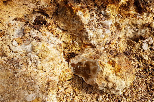 Raw texture of brown silicified limestone embedded in a mineral-rich quarry wall, highlighting the geological formation and rugged layers of natural stone sediment