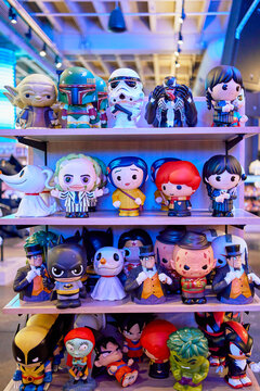 Collection of various pop culture character vinyl figures and bobbleheads displayed on shelves in a store