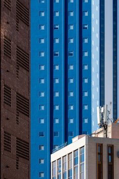 Blue residential tower rises between Benidorm Spain apartment facades, where urban resort architecture stacks windows under clear coastal sky