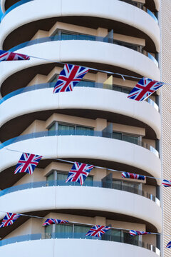 British flags wrap around curved balconies on Benidorm Spain apartment facade, where white highrise architecture meets blue resort sky