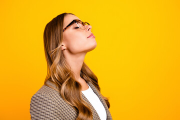 Confident woman in glasses and blazer posing profile portrait against bright yellow background for business, fashion and professional lifestyle imagery © deagreez