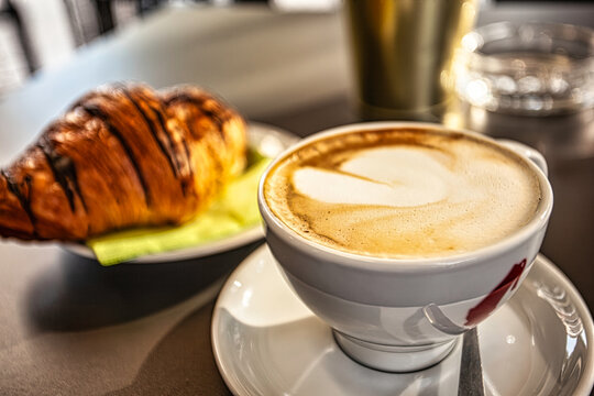 Delicious cappuccino with latte art and chocolate croissant for breakfast