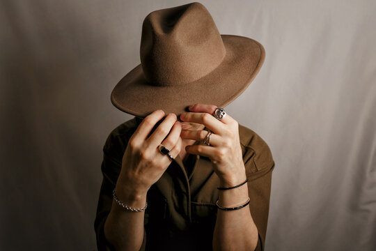 Fashion portrait of a man with his face partially concealed by a hat and hands. Concept of mystery, anonymity, confidence, privacy and modern masculine style.

