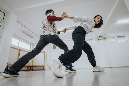 Two dancers practice a partnered contemporary routine in a bright studio. A dynamic low-angle shot captures their movement and connection during rehearsal