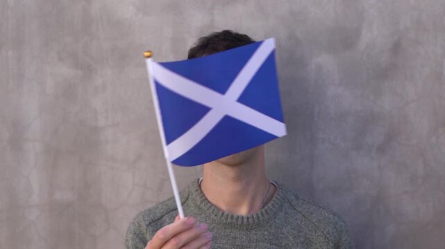 Close up shot of a man waving Scottish flag in slow motion. Scotland country flag.