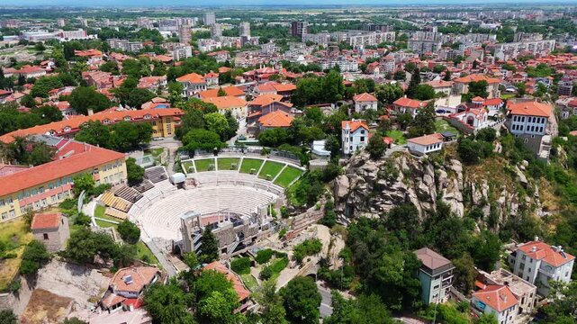 aerial drone panorama showcasing the Roman Theatre of Philippopolis nestled within the historic old town district and sweeping cityscape of Plovdiv under a clear sky, Bulgaria