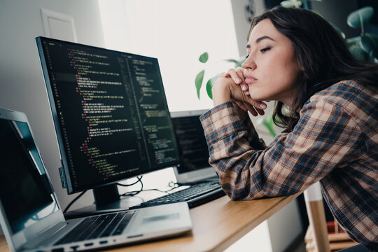 Woman programmer coding at home desk, bored developer staring at computer screens during remote work session