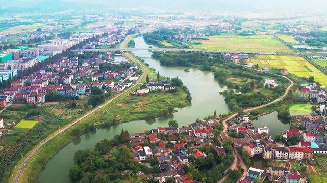 Aerial view of suburban town with winding river bridge and farmland