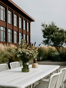 Modern Rooftop Terrace With Outdoor Dining Table and Chairs Surrounded by Potted Plants Overlooking City Skyline at Dusk