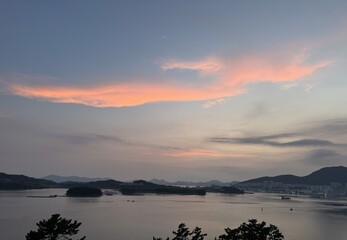 Fototapeta premium Pink sunset glow over a calm coastal bay with islands and pine tree silhouettes